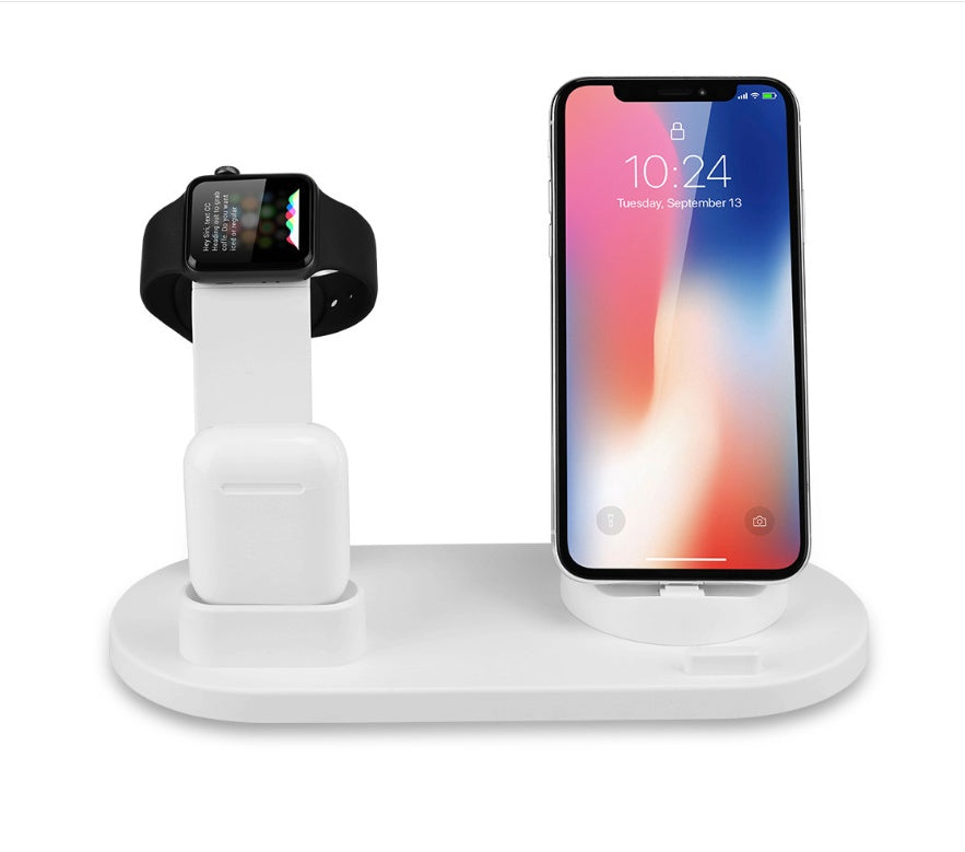 White 3-in-1 charging station holding a black smartwatch, wireless earbuds case, and smartphone with lock screen