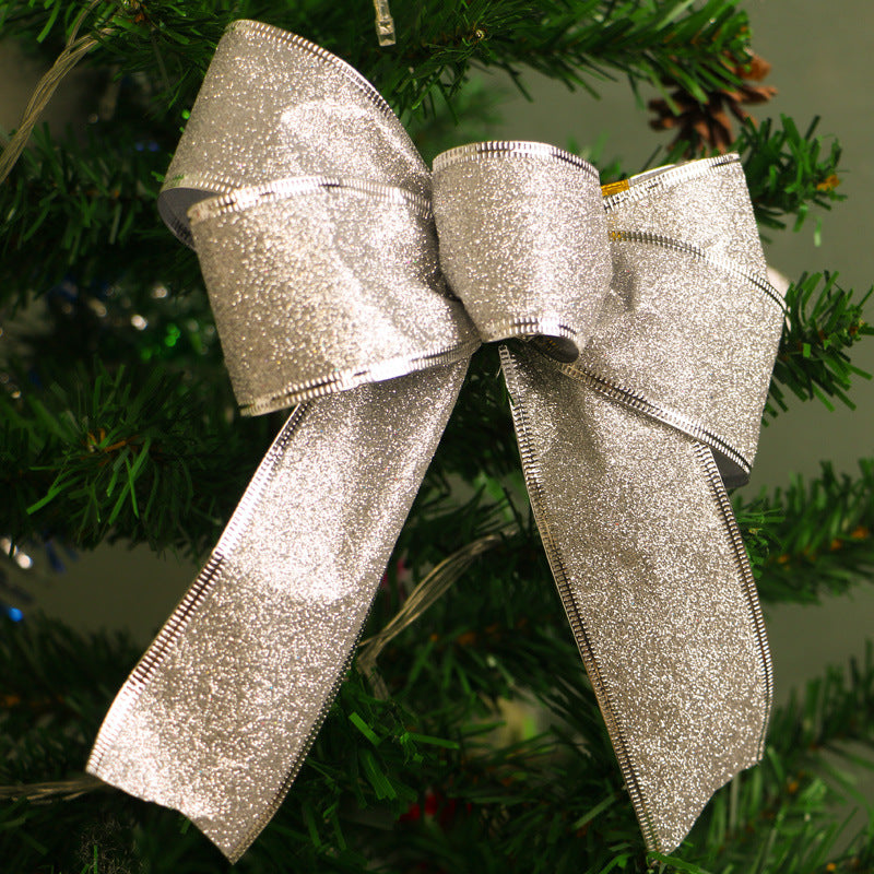 Silver glittery ribbon bow decoration on green Christmas tree branch