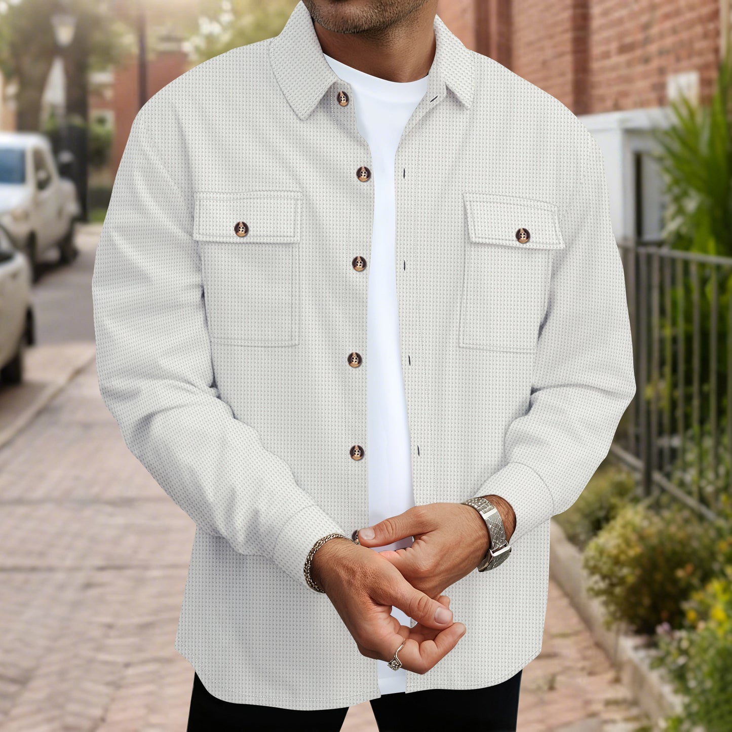 Man wearing white textured button-up shirt with flap pockets and silver watch outdoors