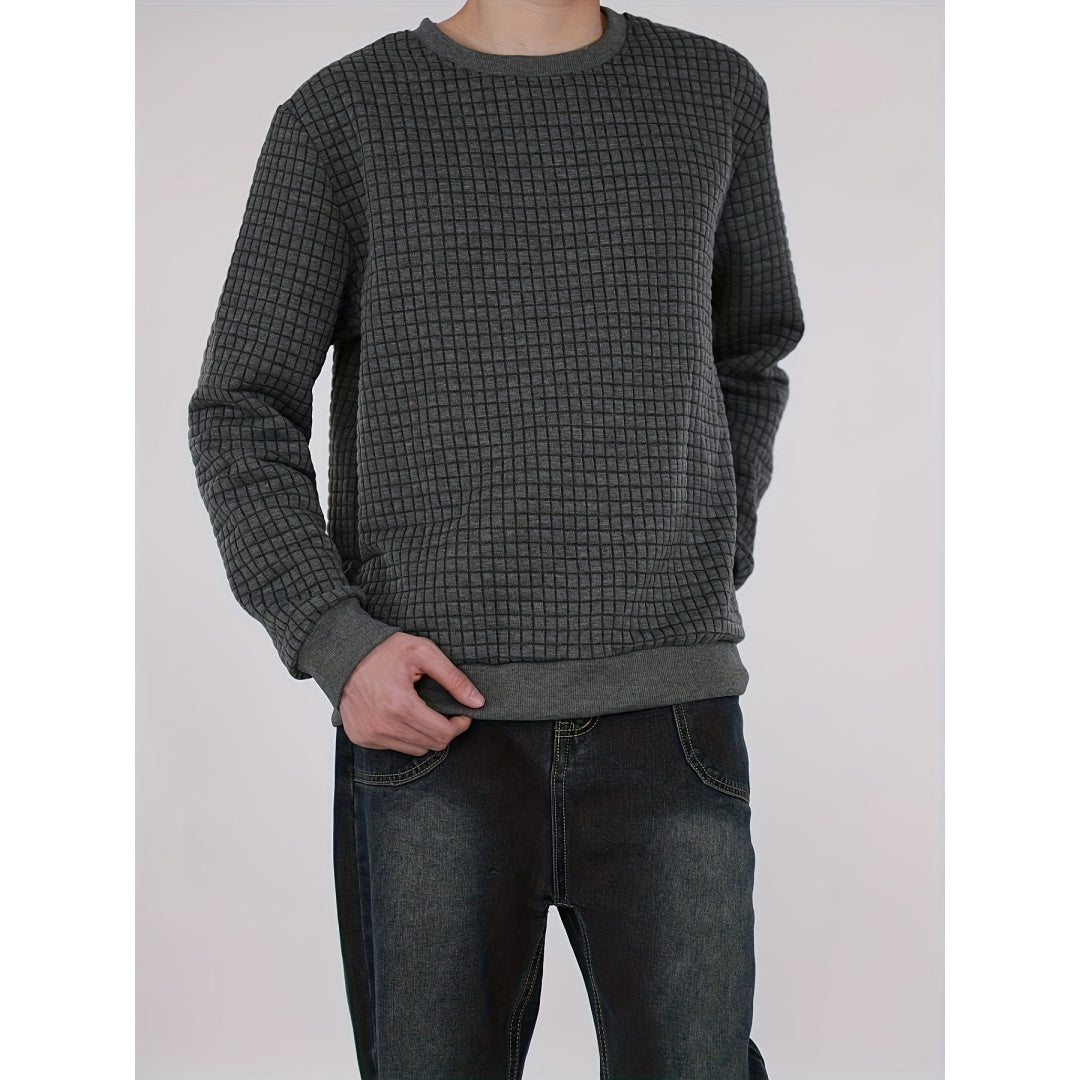 Man wearing dark gray textured checkered sweater with black washed jeans in studio