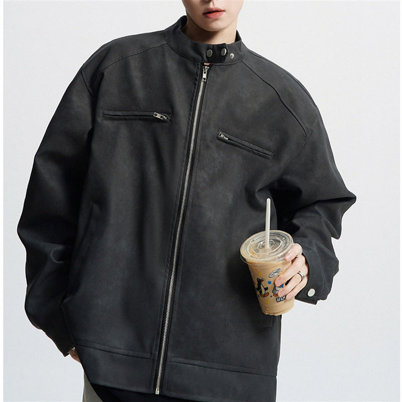 Person wearing oversized black leather jacket with zippered pockets holding iced coffee cup