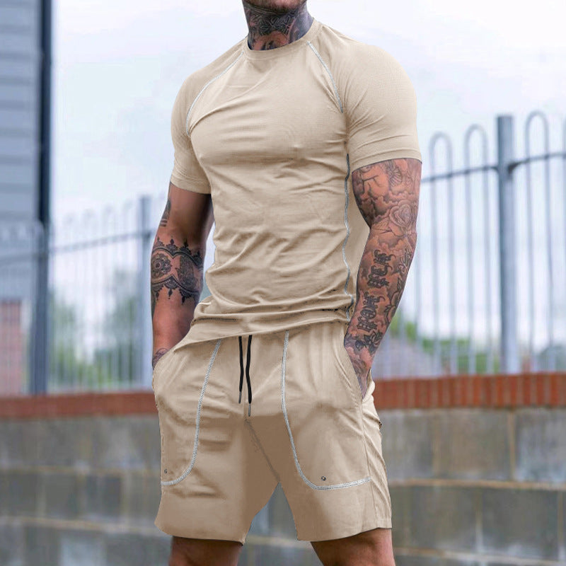Muscular man with tattoos wearing beige short-sleeve shirt and matching shorts outdoors