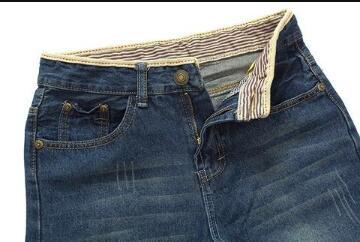 Close-up of men's slim fit blue denim jeans with striped inner waistband and casual worn detailing
