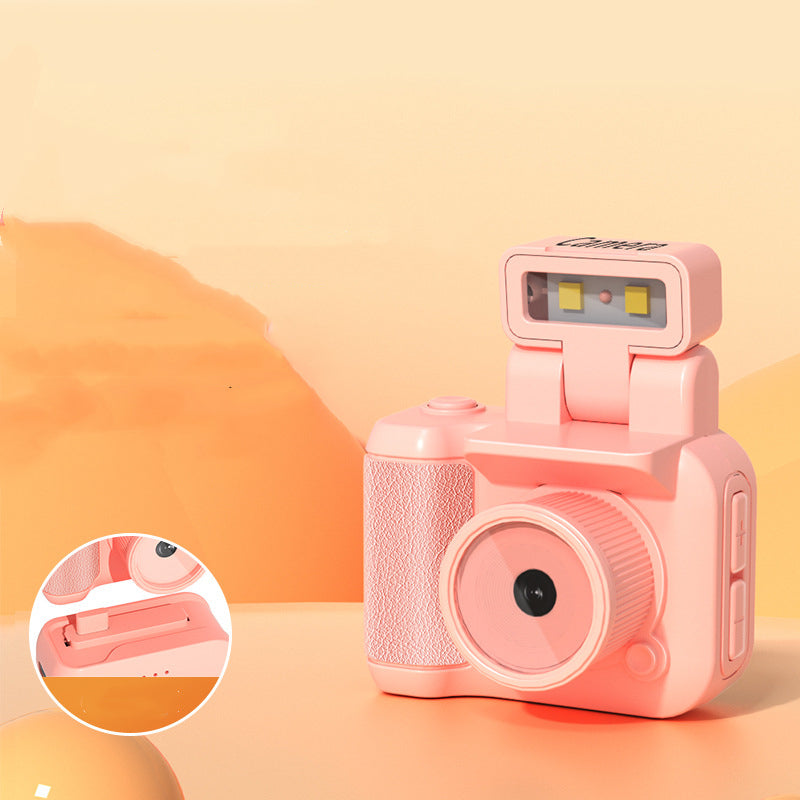 Retro-style pink toy digital camera with flash, textured grip, and volume buttons on soft orange background