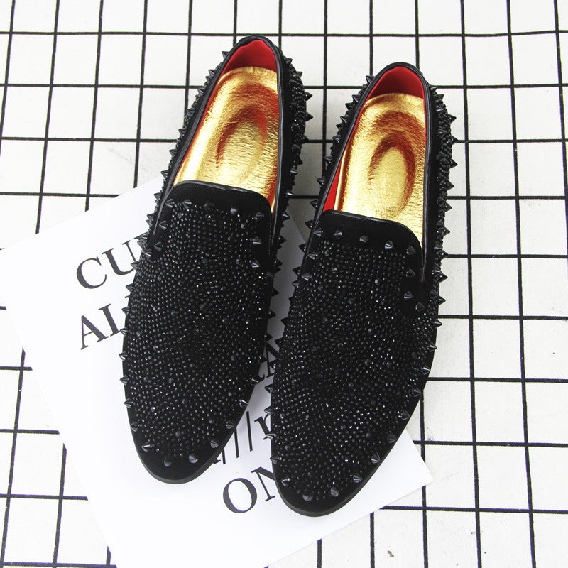 Men's black loafers with pointed toe, studded upper, and gold inner lining on grid background