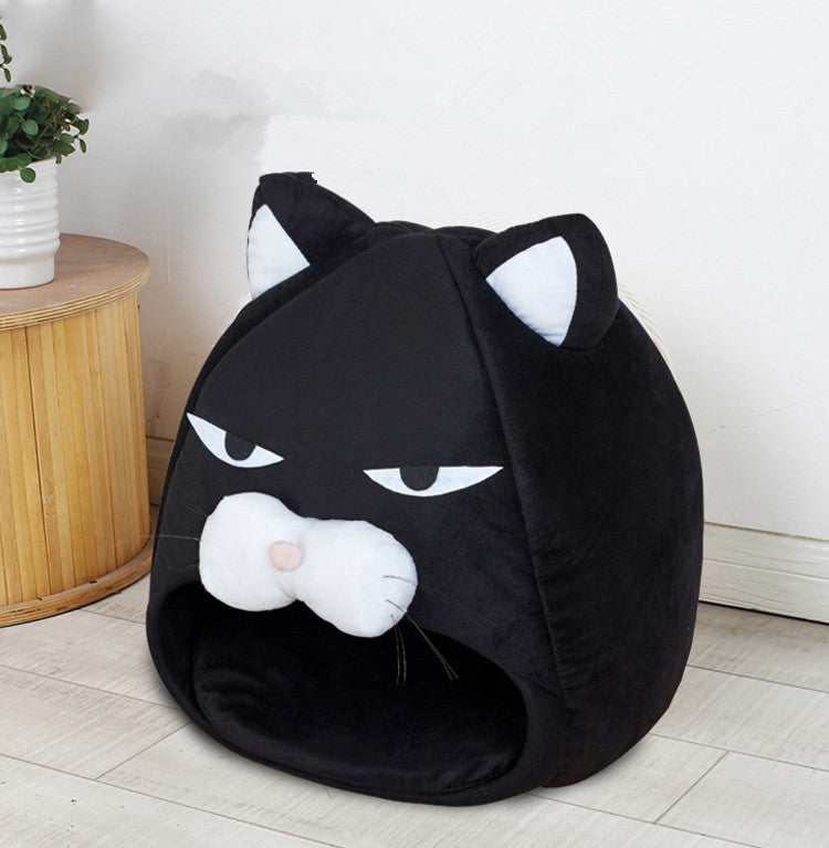 Black cat-shaped plush pet bed with white ears and snout, placed on light wood floor