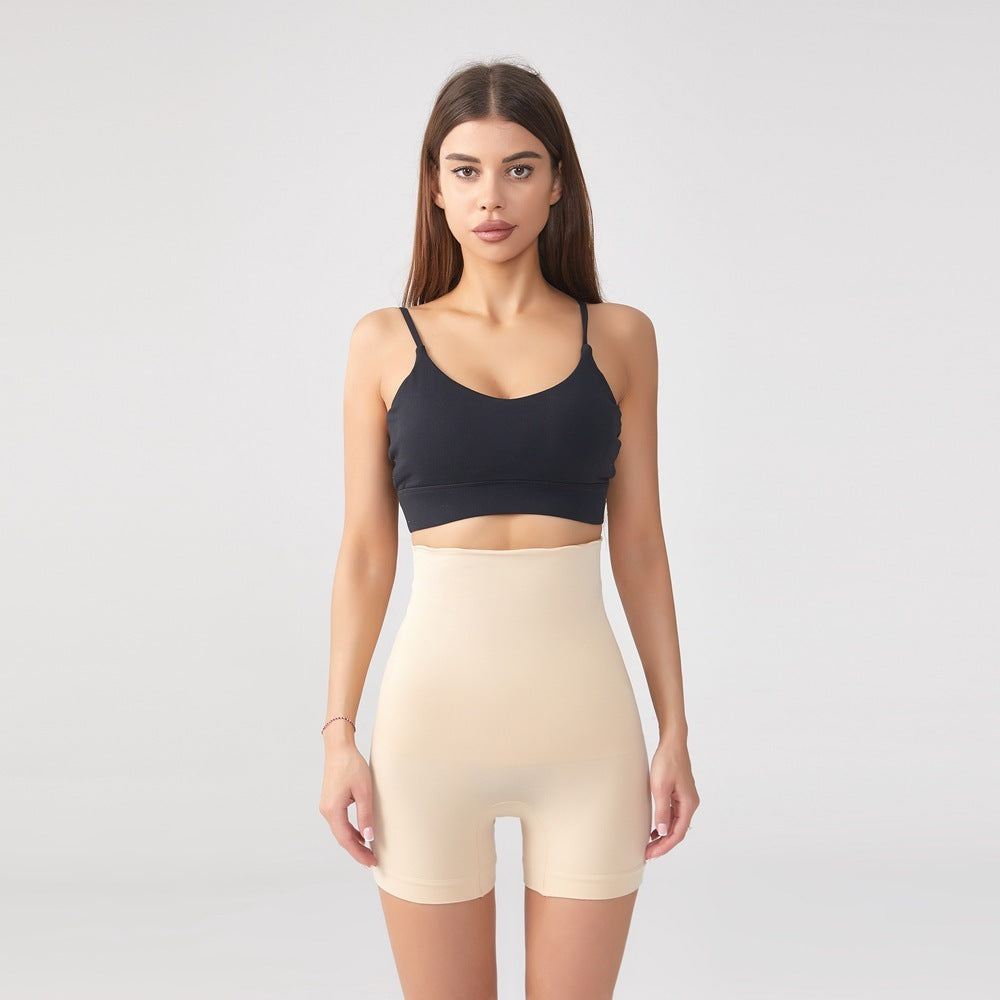Woman wearing beige high-waist shaping shorts and black sports bra on gray background