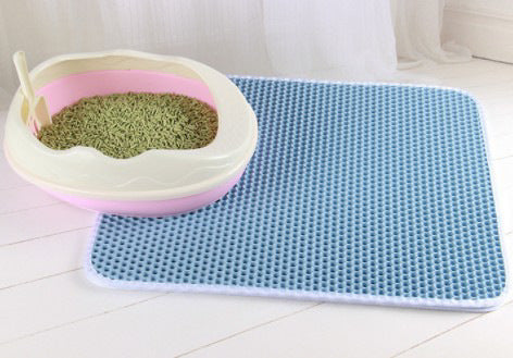 Pink cat litter box with green pellet litter and scoop on a blue honeycomb waterproof cat litter mat