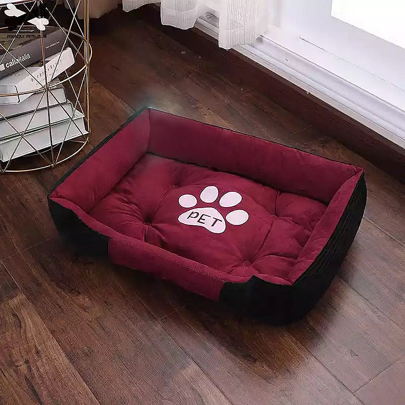 Rectangular red and black cozy pet bed with a white paw print and 'PET' text, placed on wooden floor