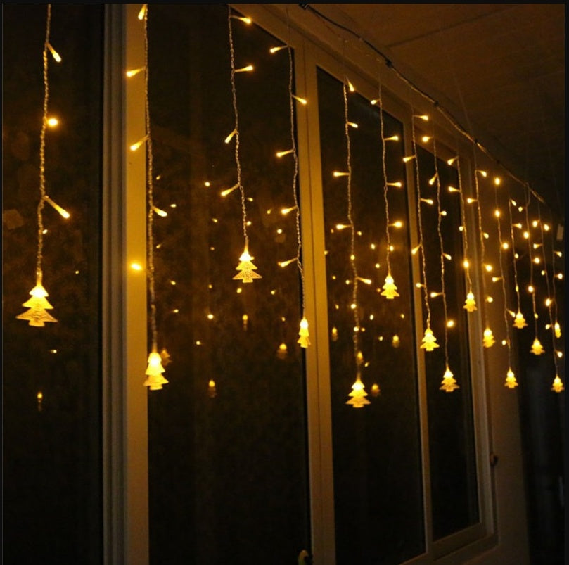 Warm yellow Christmas tree icicle string lights hanging on window at night for festive decoration