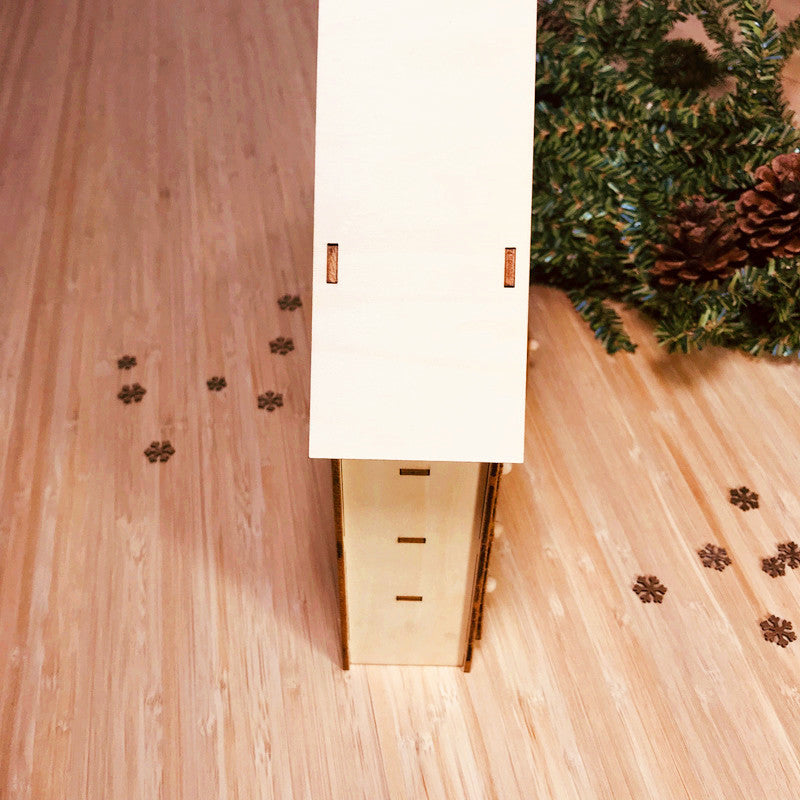 DIY wooden Christmas advent calendar standing on wood surface with pine cones and evergreen branches