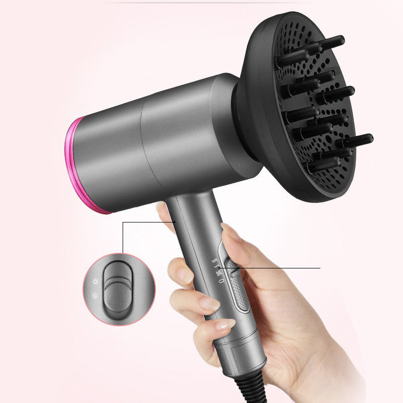 Hand holding a gray ionic hair dryer with a black diffuser attachment and visible control switches