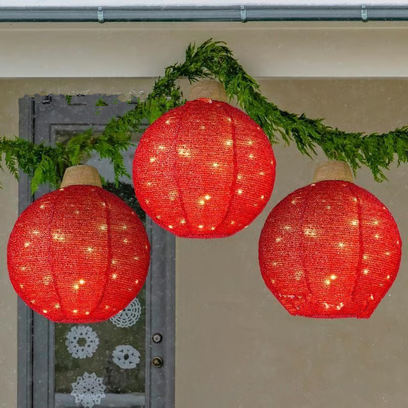 Three glowing red round lanterns hanging with green pine garland outside a door with snowflake decorations