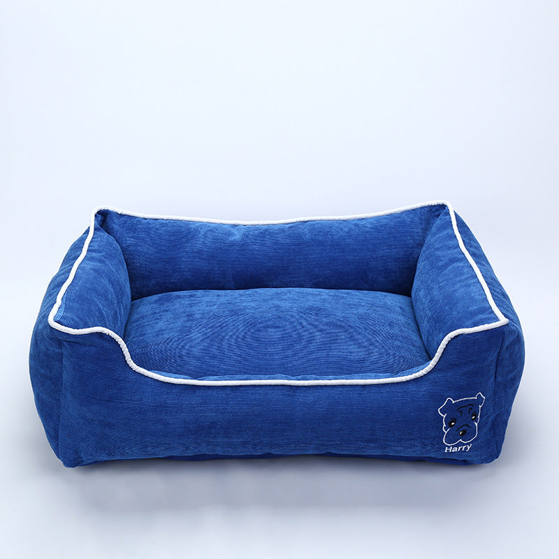 Blue corduroy dog bed with white piping and embroidered dog face labeled Harry on front