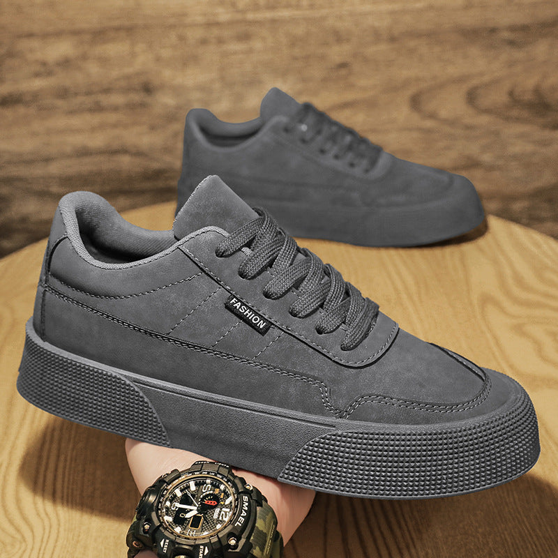Close-up of grey men's casual sneakers with thick textured sole and lace-up design on wooden surface