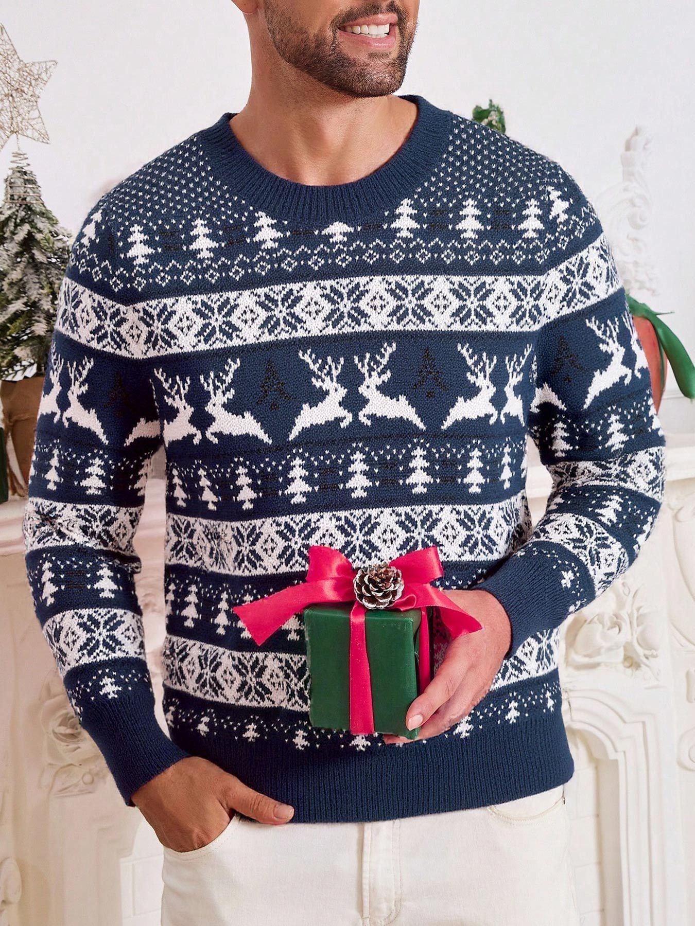 Man wearing navy blue and white Christmas sweater with reindeer and trees, holding green gift box with red ribbon