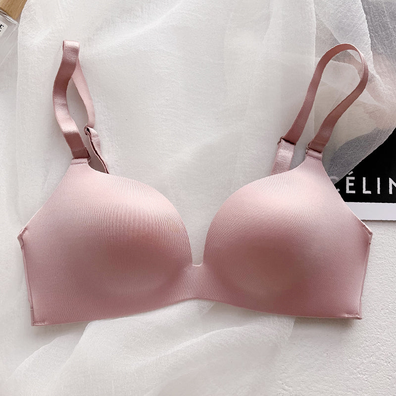 Pink wireless push-up bra with thin seamless cups and adjustable straps on white fabric background