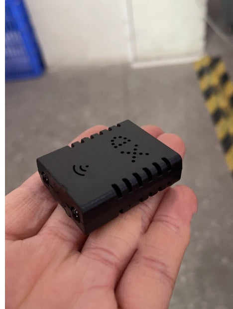 Hand holding a small black wireless device with vent holes and WiFi symbol on top