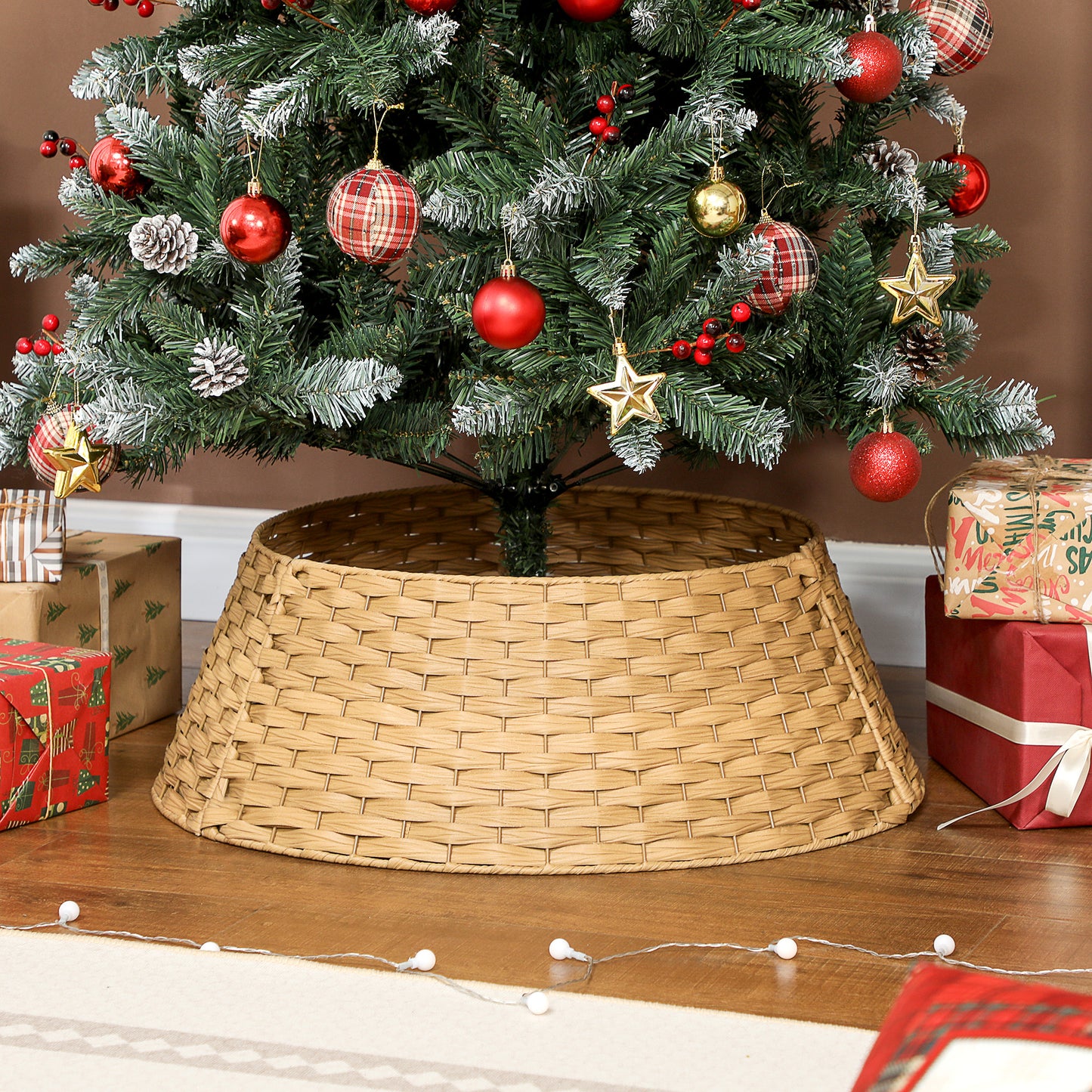 Decorated Christmas tree with red, gold ornaments and pinecones in a woven coffee-colored tree collar on wooden floor