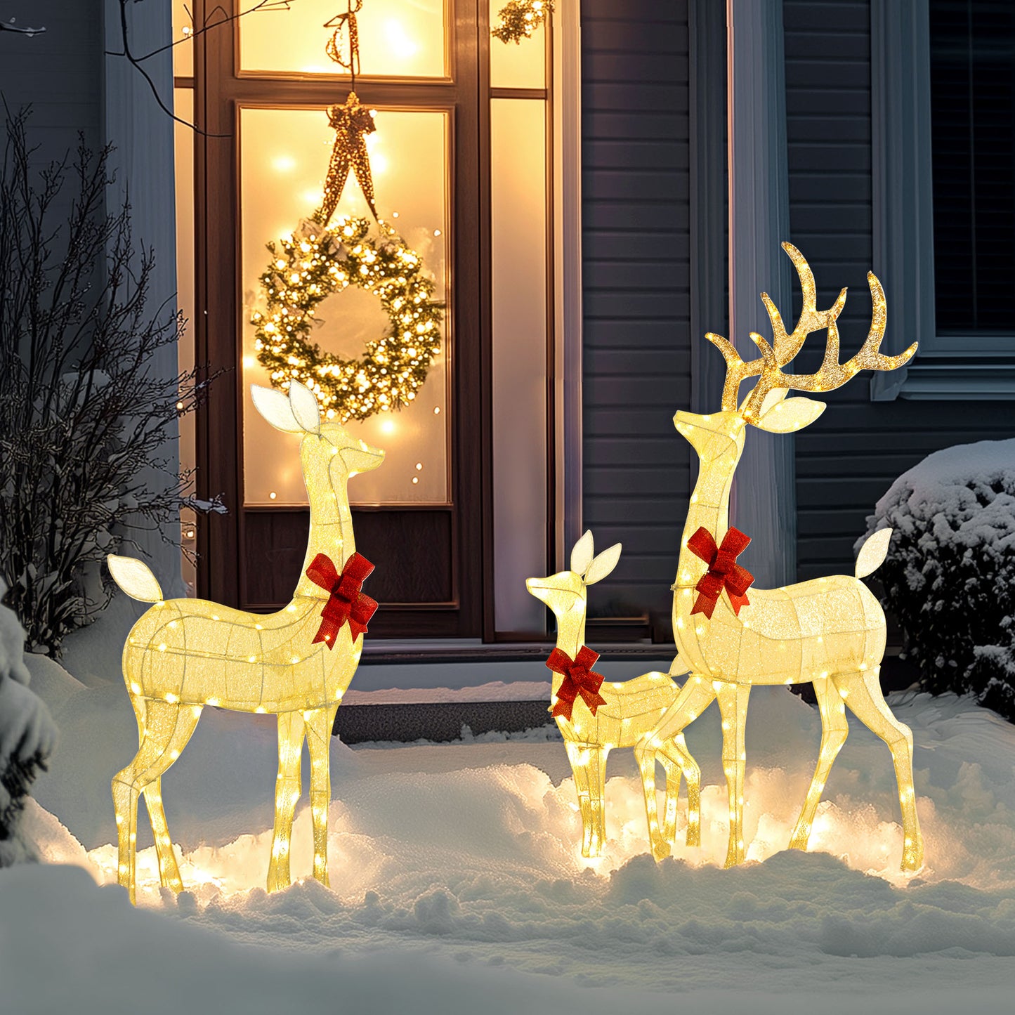 Outdoor Christmas decoration with three lighted gold reindeer with red bows in snowy front yard