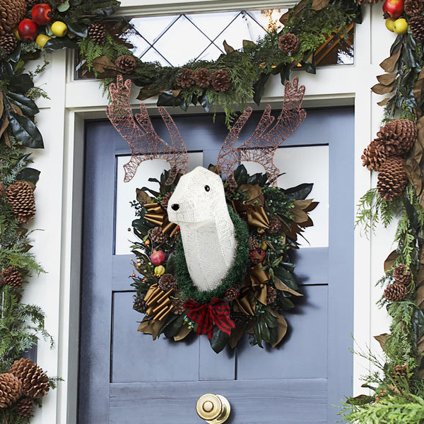 Christmas wreath with lighted white reindeer head and decorative pinecones on blue front door