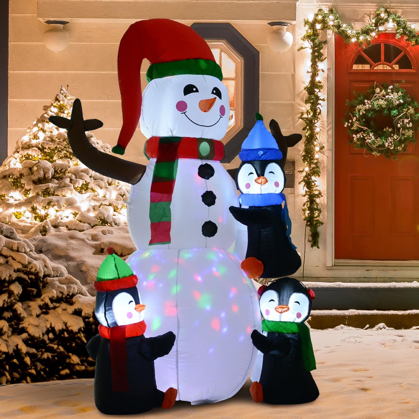 Inflatable LED snowman wearing red hat and scarf with three penguins in winter hats and scarves by house entrance