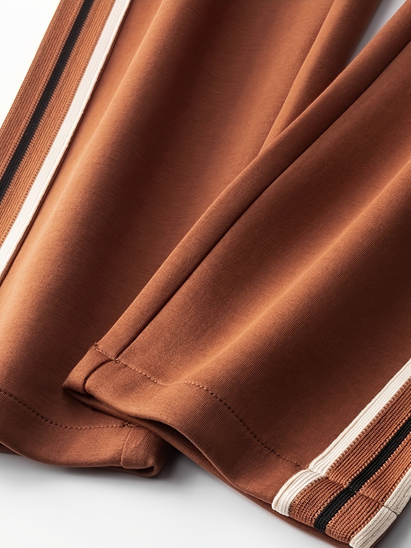 Close-up of brown fabric with white and black striped ribbed cuffs, showing texture and stitching details