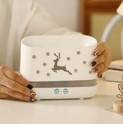 White humidifier with reindeer and snowflake designs held by hands with colorful glittery nails on white table