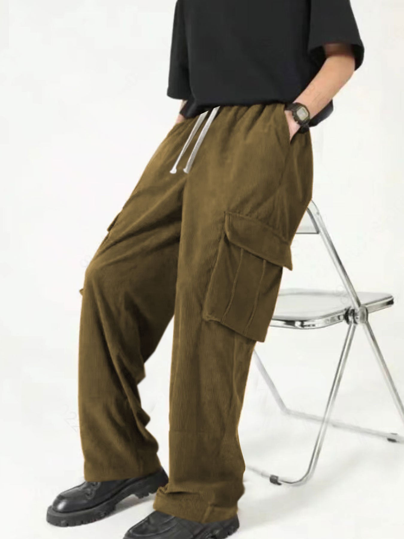 Person wearing brown cargo pants with drawstring and black shoes sitting on a metal folding chair