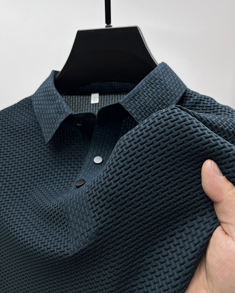 Close-up of dark textured polo shirt on black hanger with hand holding fabric showing pattern