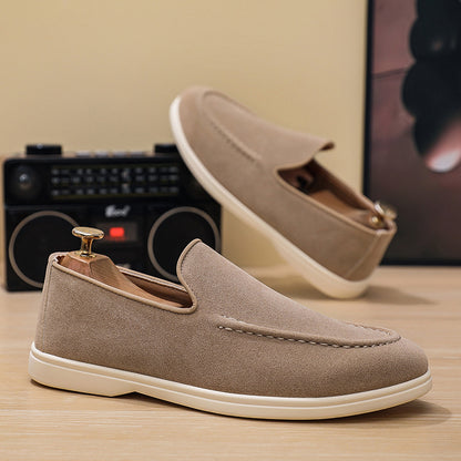 Taupe suede casual slip-on loafers with white soles displayed on wooden surface