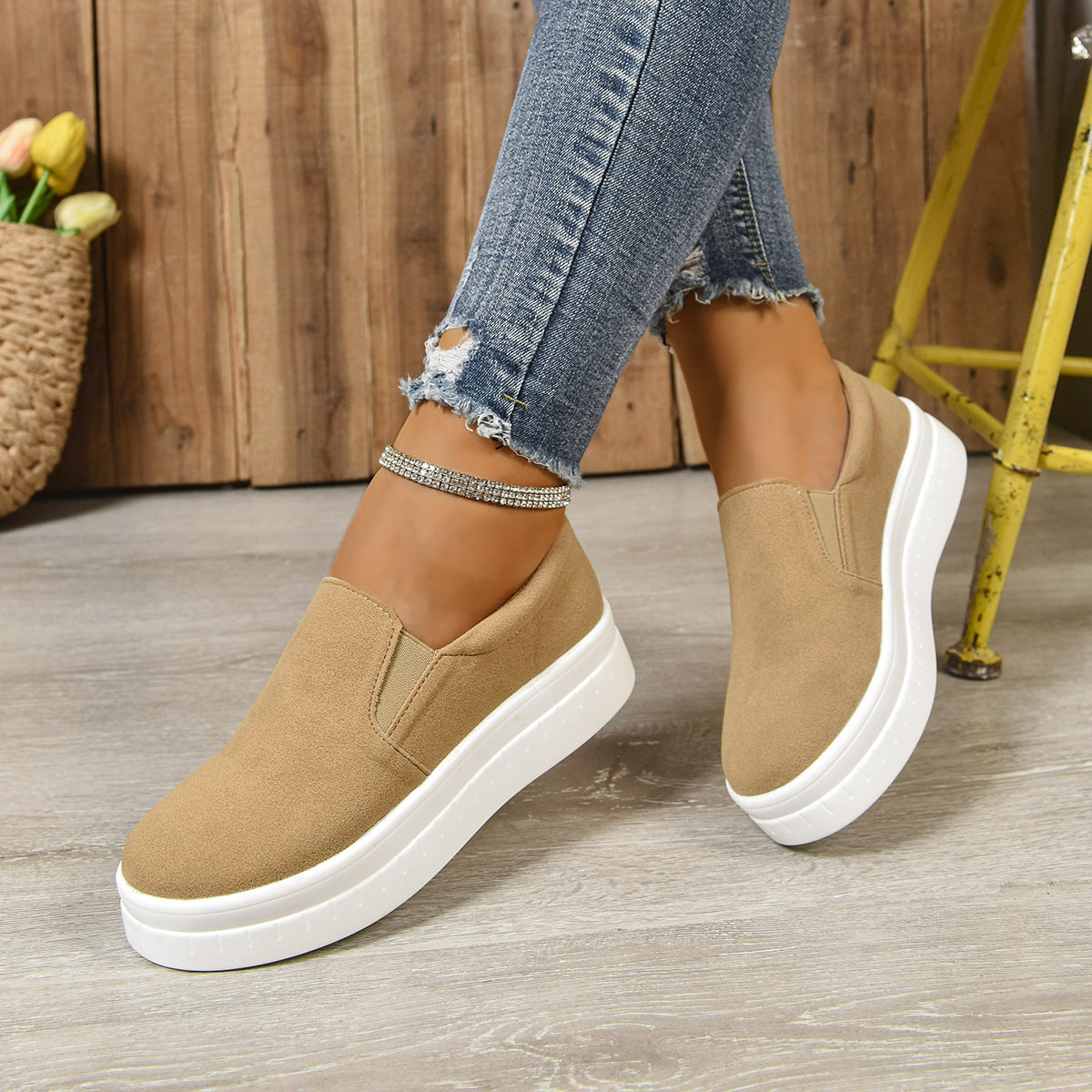 Women wearing beige slip-on platform sneakers with white soles and ripped skinny jeans