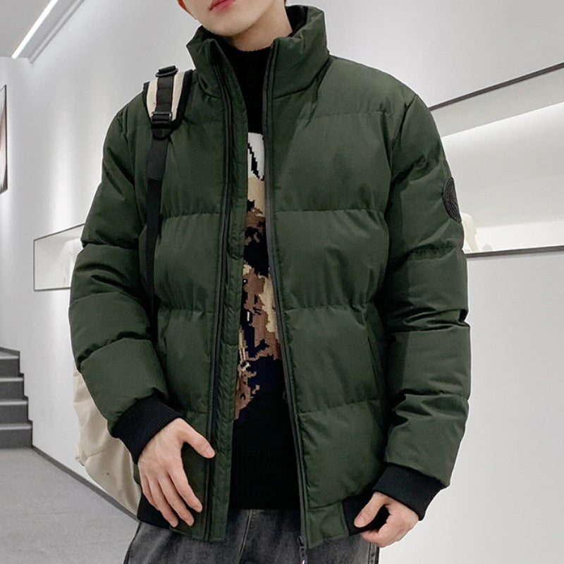 Man wearing a dark green padded winter jacket with black cuffs indoors