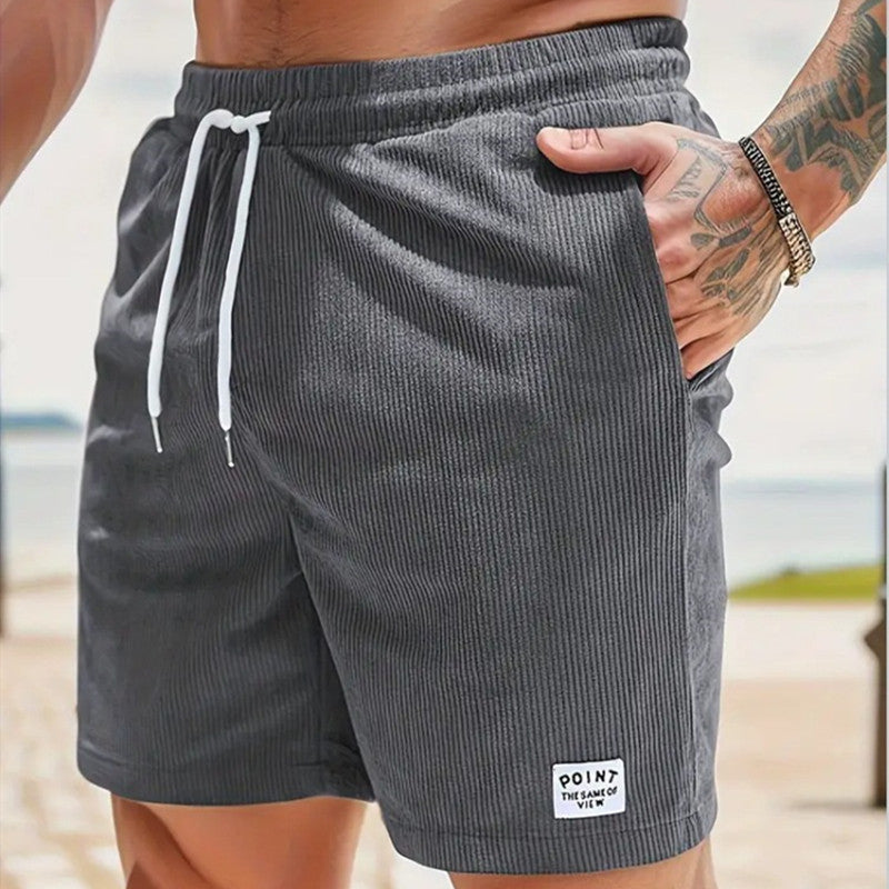 Close-up of man wearing gray ribbed knit shorts with white drawstring and pocket patch outdoors