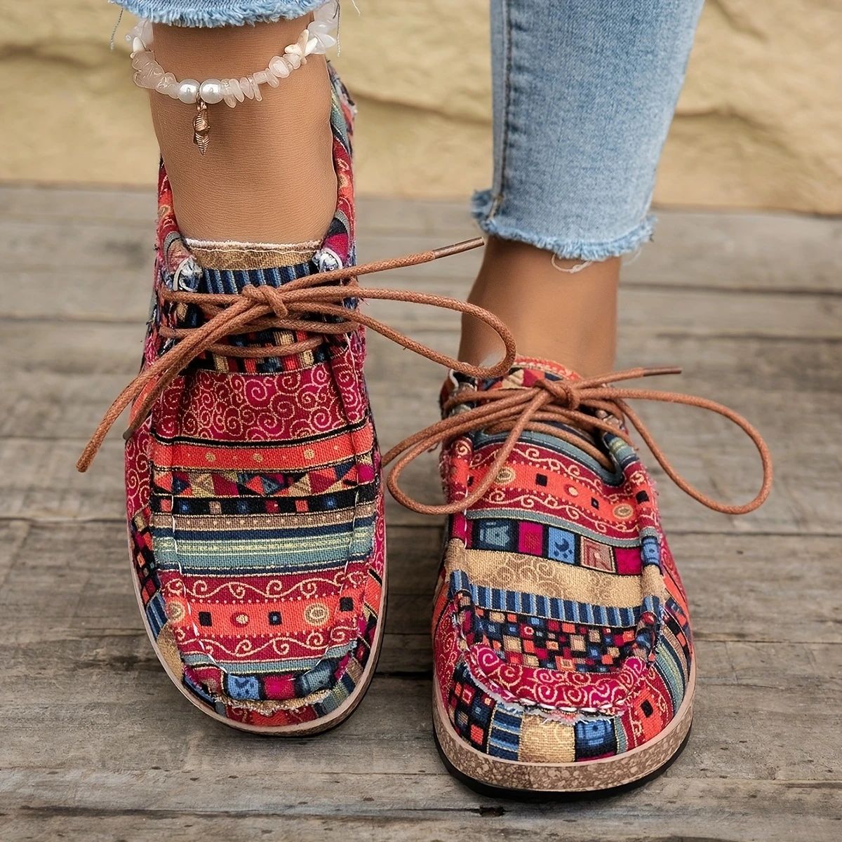 Colorful patterned fabric shoes with brown laces worn with light blue frayed jeans and a pearl anklet