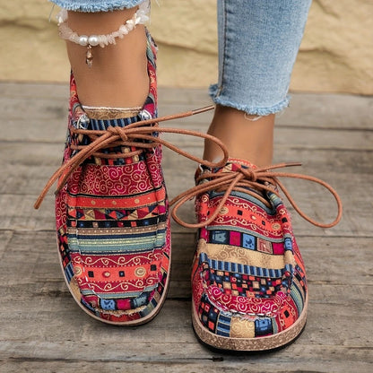 Colorful patterned casual shoes with brown laces worn with light blue cropped jeans on wooden floor