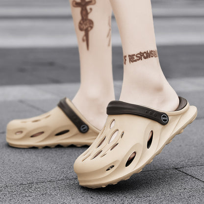 Beige slip-on clogs with black adjustable strap worn on feet with ankle tattoos on gray pavement