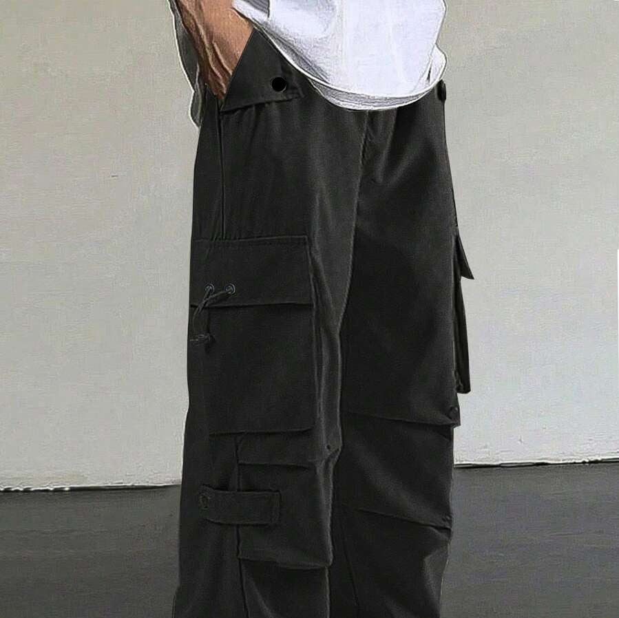 Close-up of black cargo pants with multiple pockets and button details, worn with white shirt