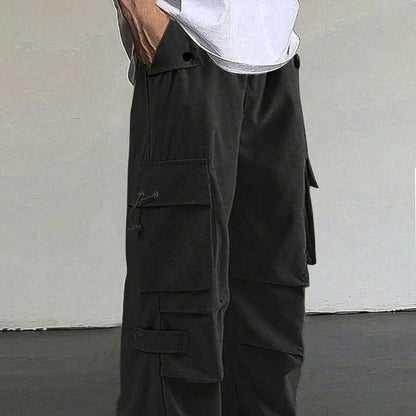 Close-up of black cargo pants with multiple pockets and button details, worn with white shirt