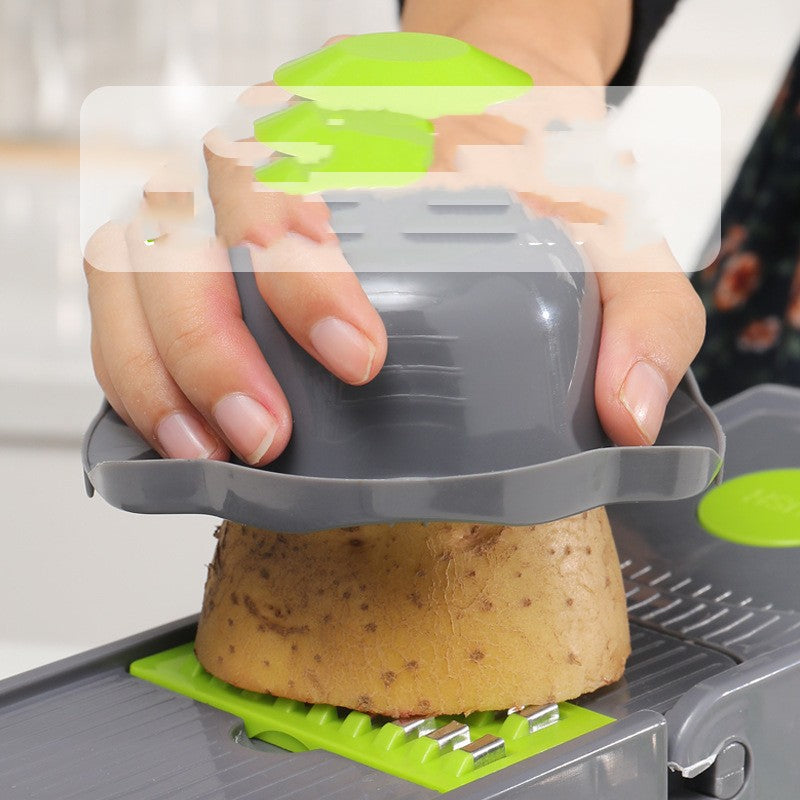 Hand using gray and green vegetable slicer to cut a potato in kitchen setting