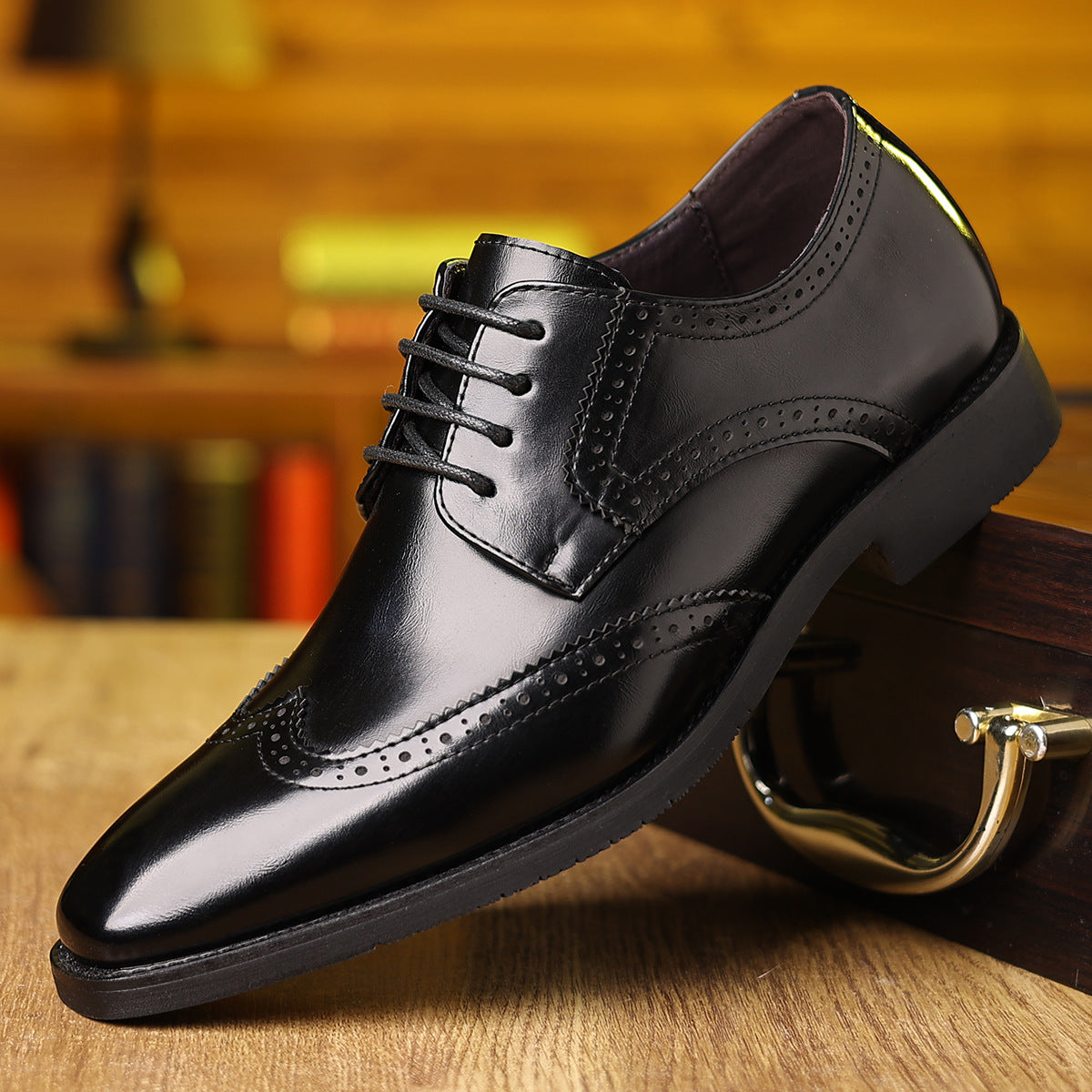 Black polished men's wingtip dress shoe with brogue detailing on wooden surface near leather briefcase