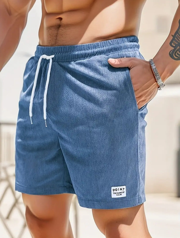 Close-up of man wearing blue ribbed drawstring shorts with pocket and wrist bracelet