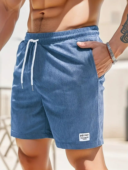 Close-up of man wearing blue ribbed drawstring shorts with pocket and wrist bracelet