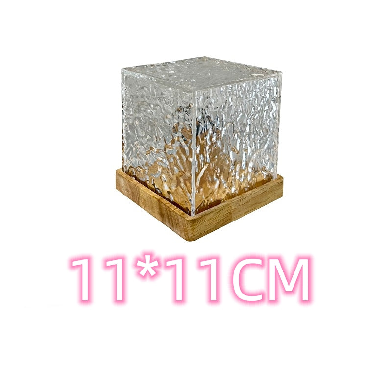Textured clear glass cube with wooden base measuring 11 by 11 cm on white background