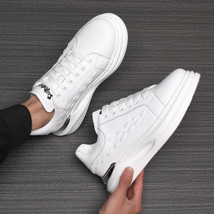 White leather sneakers with textured side design and thick white soles on dark wood surface