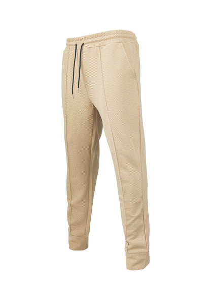 Beige textured jogger pants with black drawstrings and elastic waistband on white background
