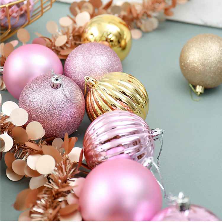 Pink, gold, and rose gold Christmas baubles with glitter and metallic finishes on a green surface