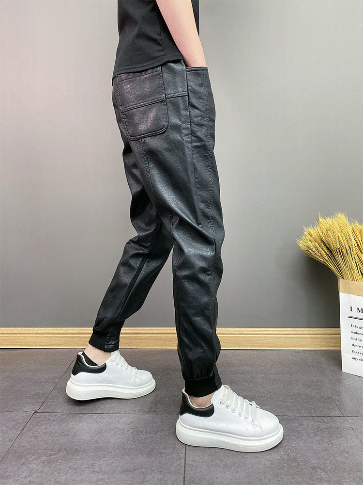 Person wearing black faux leather jogger pants with back pockets and white platform sneakers on gray tile floor