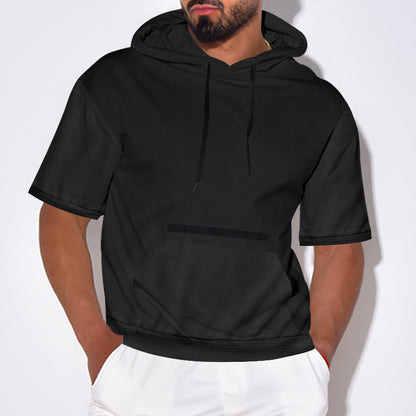 Man wearing black short-sleeve hoodie with front pocket and white pants against white background