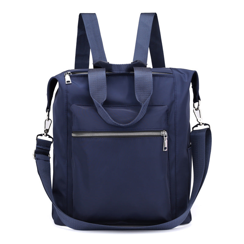 Navy blue backpack tote bag with front zip pocket, dual shoulder straps, and detachable crossbody strap